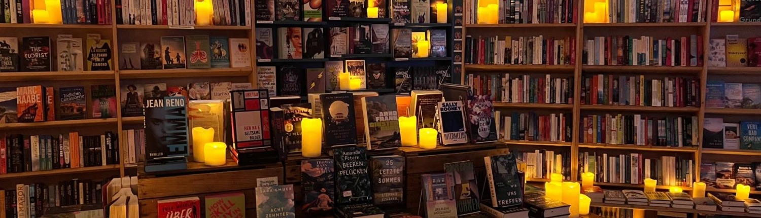 Bücherregale voll mit entzündeten Kerzen, die eine romantische Stimmung für ein Candlelight Date in einer Buchhandlung in Mülheim an der Ruhr kreieren.