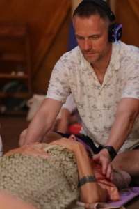 Unser Kursleiter Andreas, der während einer Breathwork Session einet teilnehmenden Person bei der Atemreise hilft.