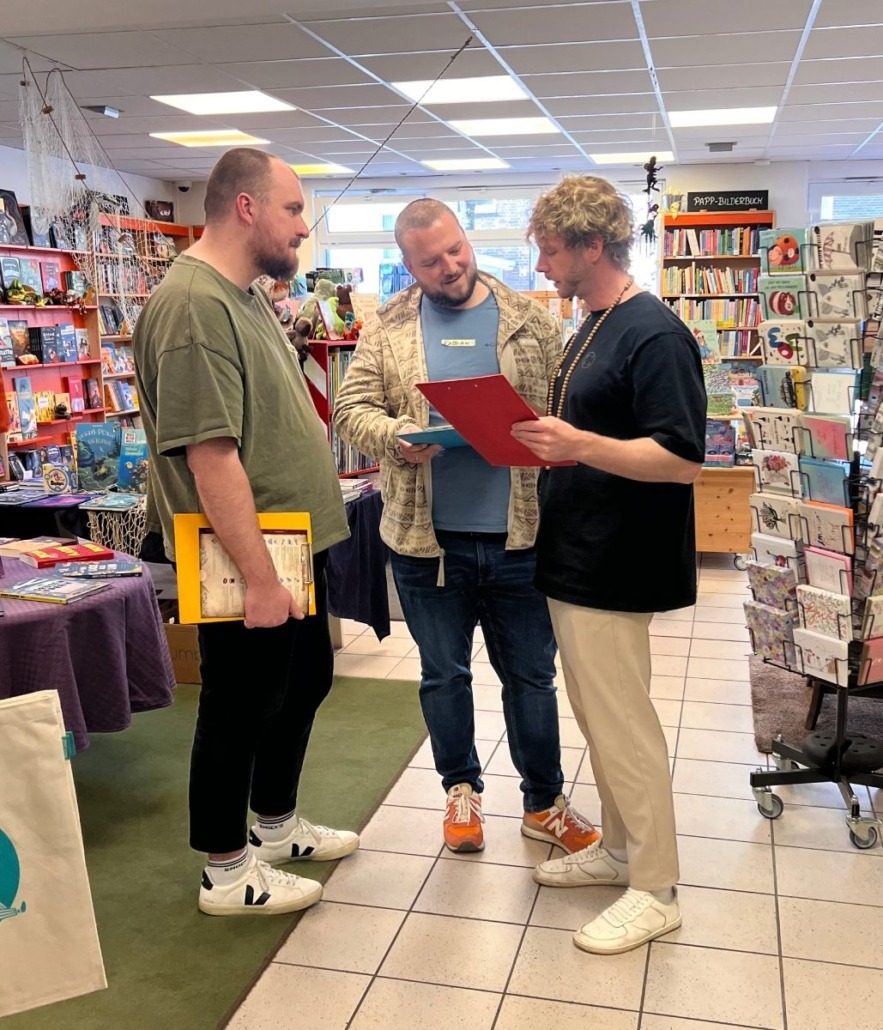 Einblick in eine Spielrunde Blood on the Clocktower in den Bücherträumen in Mülheim an der Ruhr. Eine Gruppe von drei Männern bespricht ihre Strategie.