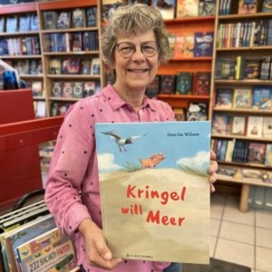 Unsere Buchhändlerin hält das Buch "Kringel will Meer" von Henrike Wilson in der Hand, zu dem sie eine Rezension geschrieben hat.