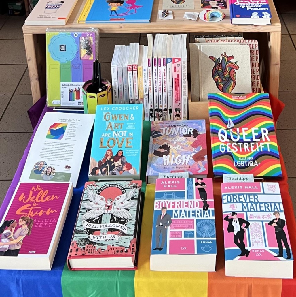 Pride Month - Queer Titelbild für einen Newsbeitrag zu verschiedenen Aktionen anlässlich des Pride Month in den Bücherträumen in Mülheim. Zu sehen ist ein dekorierter Tisch mit queeren Büchern.