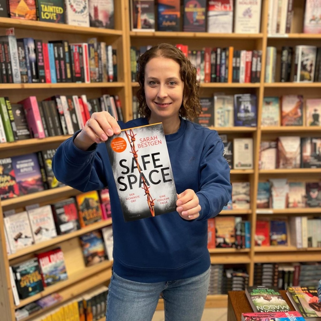 Safe Space Unsere Buchhändlerin hält das Buch "Safe Space" von Sarah Bestgen in der Hand, zu dem sie eine Rezension geschrieben hat.