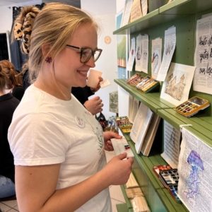Coverbild für einen Beitrag zu JGA Tipps in Mülheim. Zu sehen ist eine junge Frau, die sich bei einem Workshop in den Bücherträumen anlässlich ihres JGA umsieht.