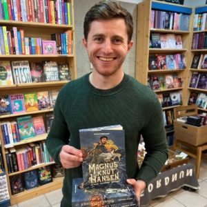 Unser Buchhändler hält das Buch "Magnus Knut Hansen" von Mikkel Robrahn in der Hand, zu dem er eine Rezension geschrieben hat.